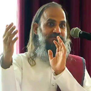 A man with long hair and a beard speaks into a microphone.